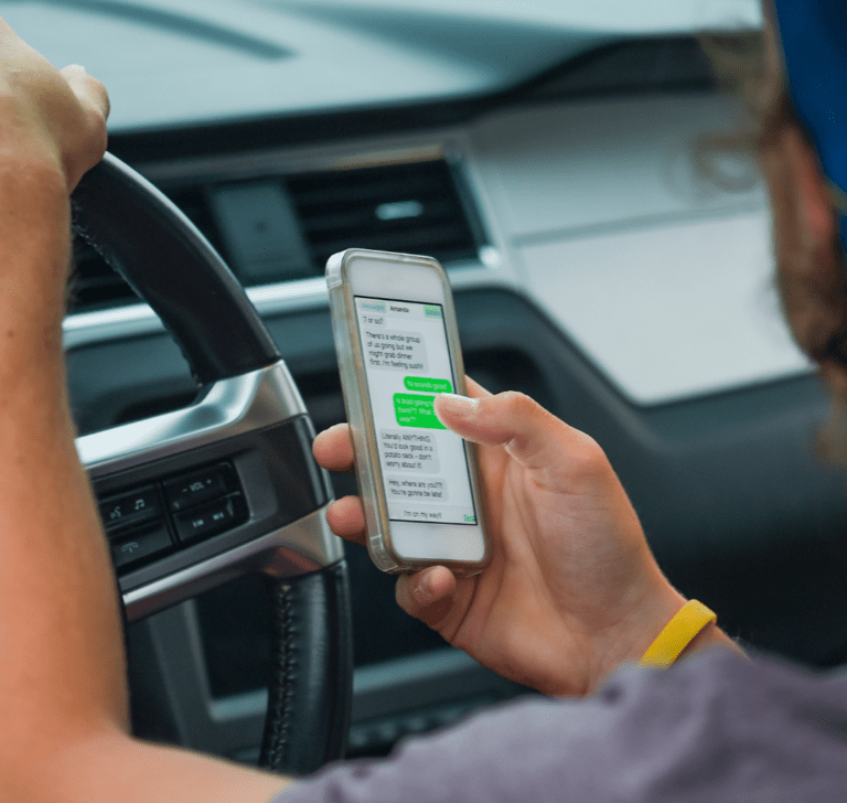 En la imagen se muestra una persona utilizando el teléfono mientras conduce