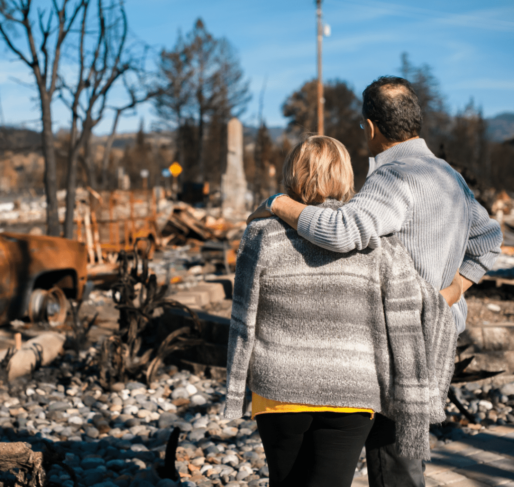 En la imagen se muestra una pareja viendo los restos de un incendio