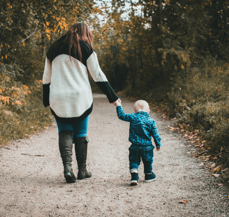 En la imagen se muestran una madre e hijo tomados de la mano de espaldas a l cámara